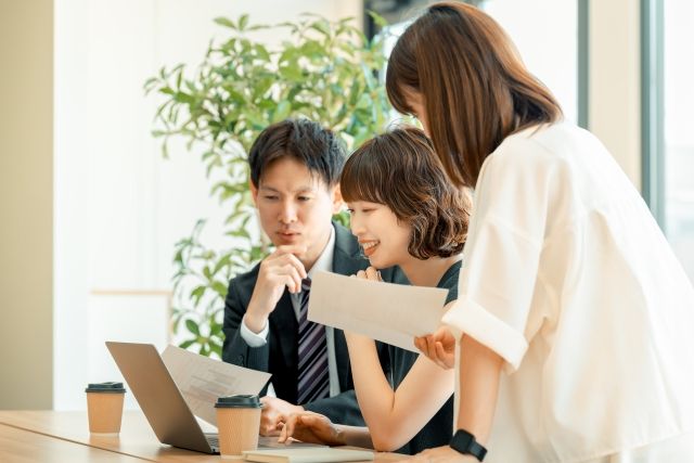 秋の明るいオフィスで相談する社労士事務所スタッフのイメージ